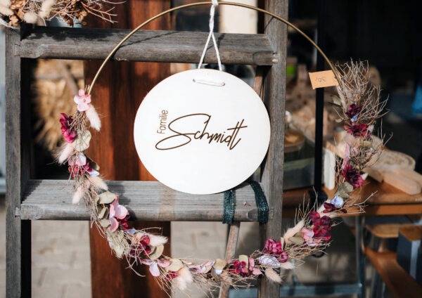 Graviertes Türschild in einem Blumenkranz