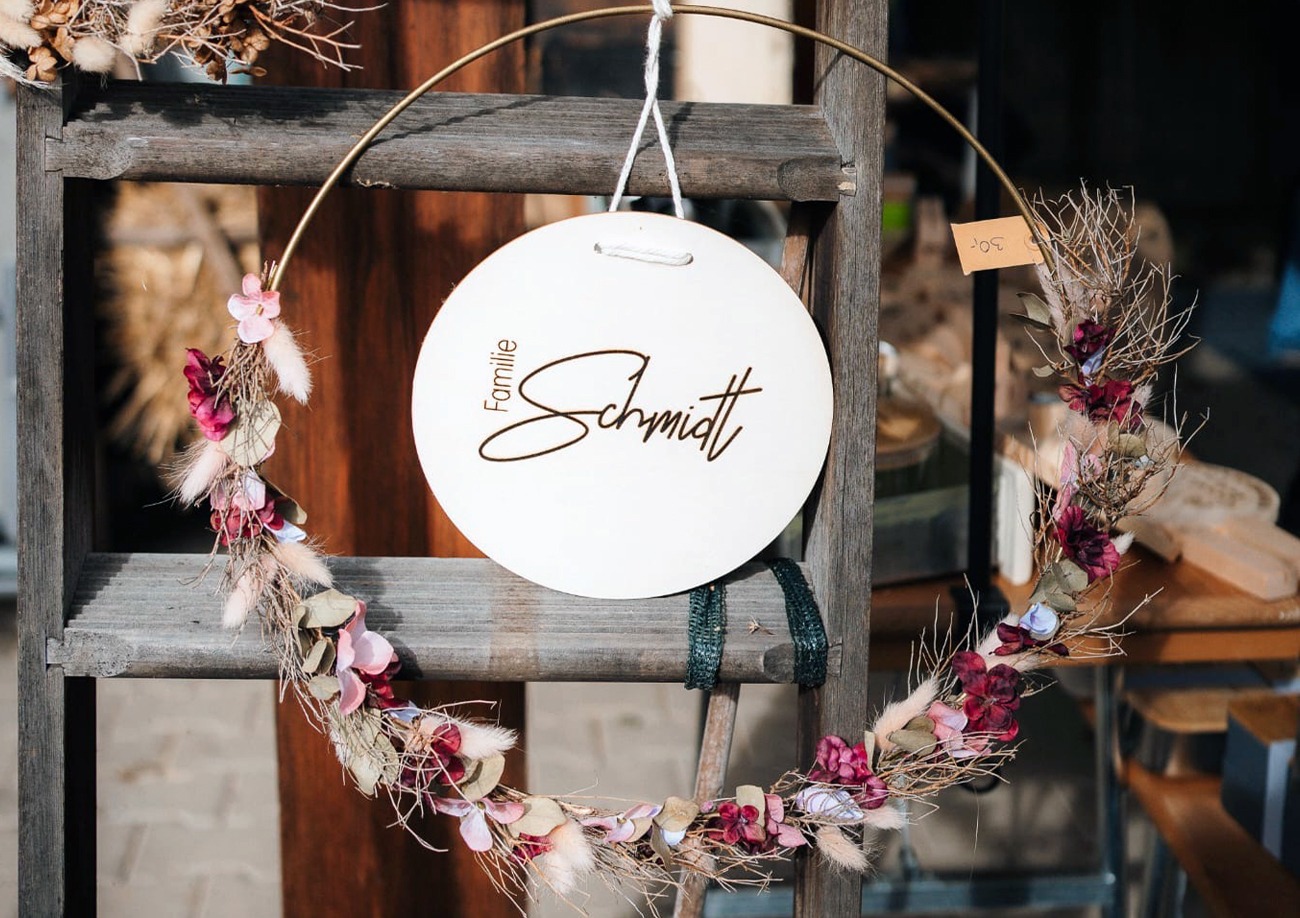 Graviertes Türschild in einem Blumenkranz